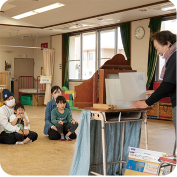 紙芝居を楽しむ親子と読み聞かせをするボランティア